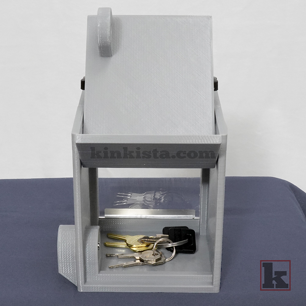 BDSM emergency keybox for control-in-absence power exchange, rear view showing press-lock with protective shroud