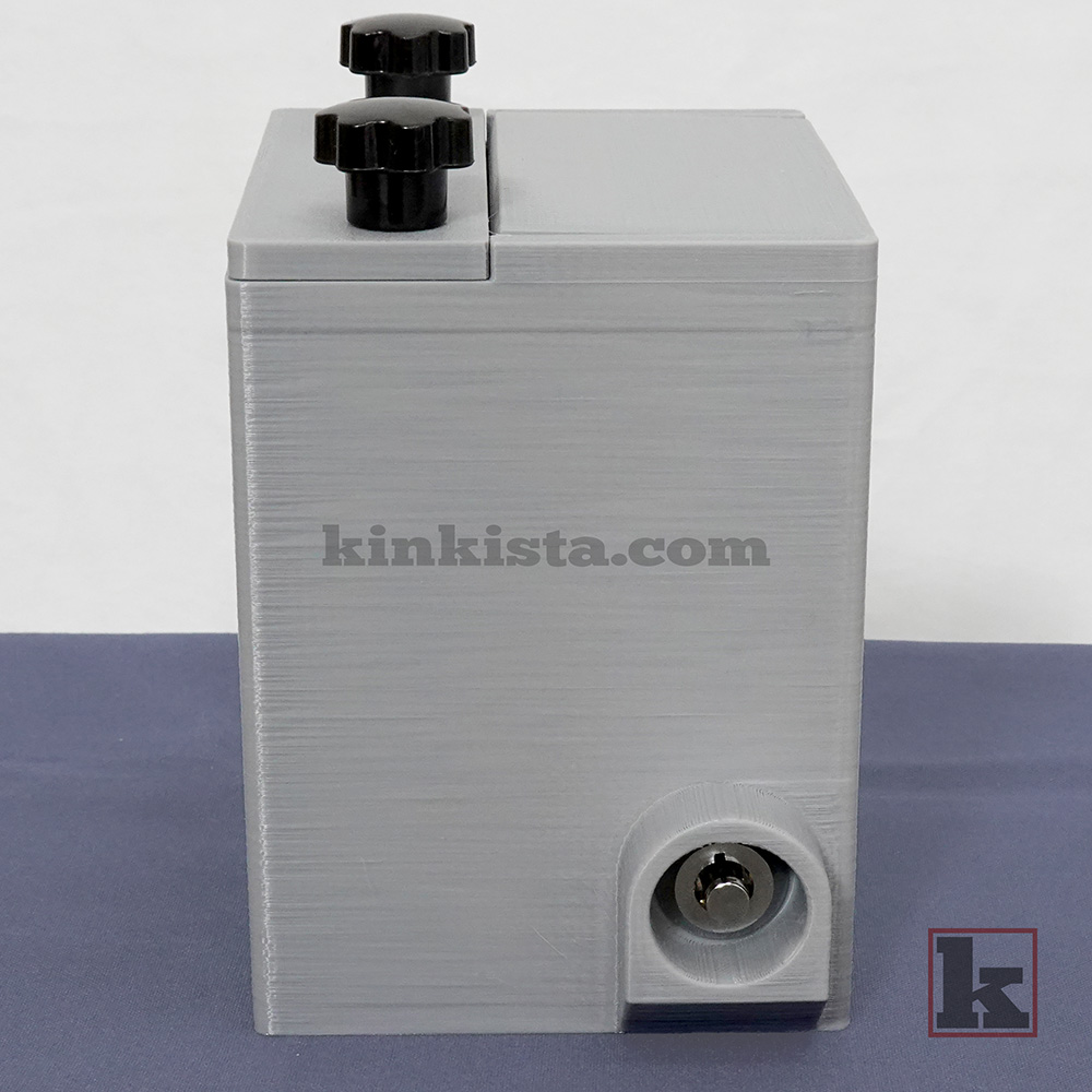 BDSM emergency keybox for control-in-absence power exchange, side view showing press-lock with protective shroud